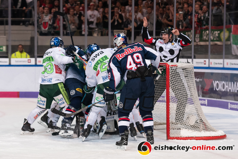 Mark Voakes (EHC Red Bull Muenchen) beobachtet, wie sich Simon Sezemsky (Augsburger Panther) und David Stieler (Augsburger Panther) intensiv mit Mads Christensen (EHC Red Bull Muenchen) beschäftigen in der 1. Halbfinalbegegnung in den Playoffs der Deutschen Eishockey Liga zwischen dem EHC Red Bull München und den Augsburger Panthern am 03.04.2019.
